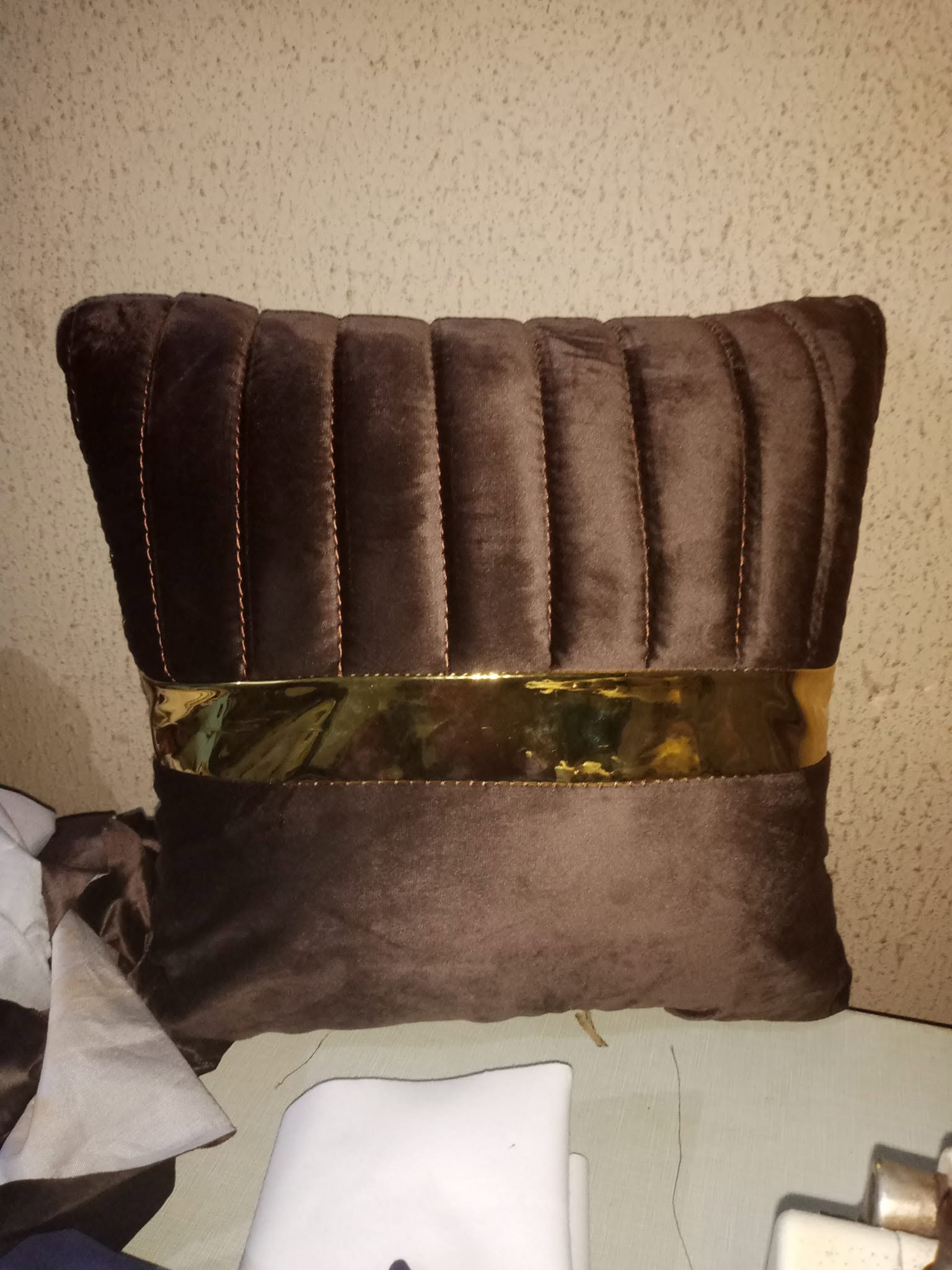 Brown velvet cushion with gold detail shown close up