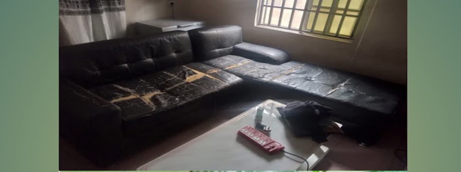 Worn black L-shaped sofa before reupholstery