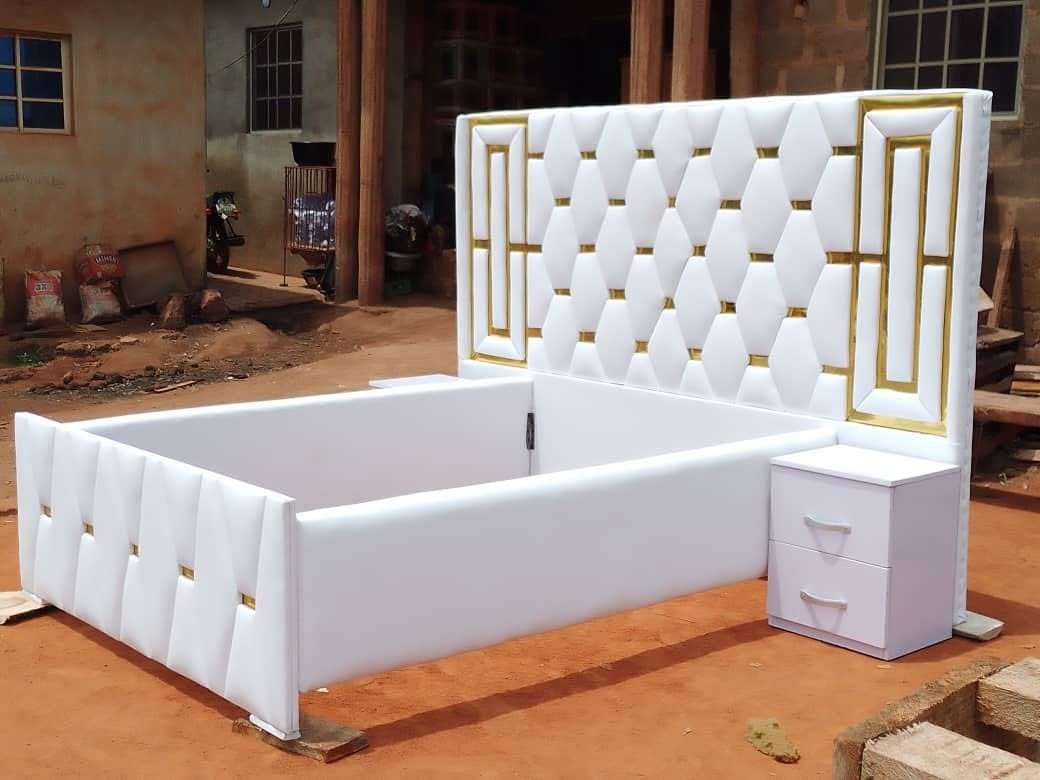 Detail view of a white and gold upholstered bedframe headboard at the workshop