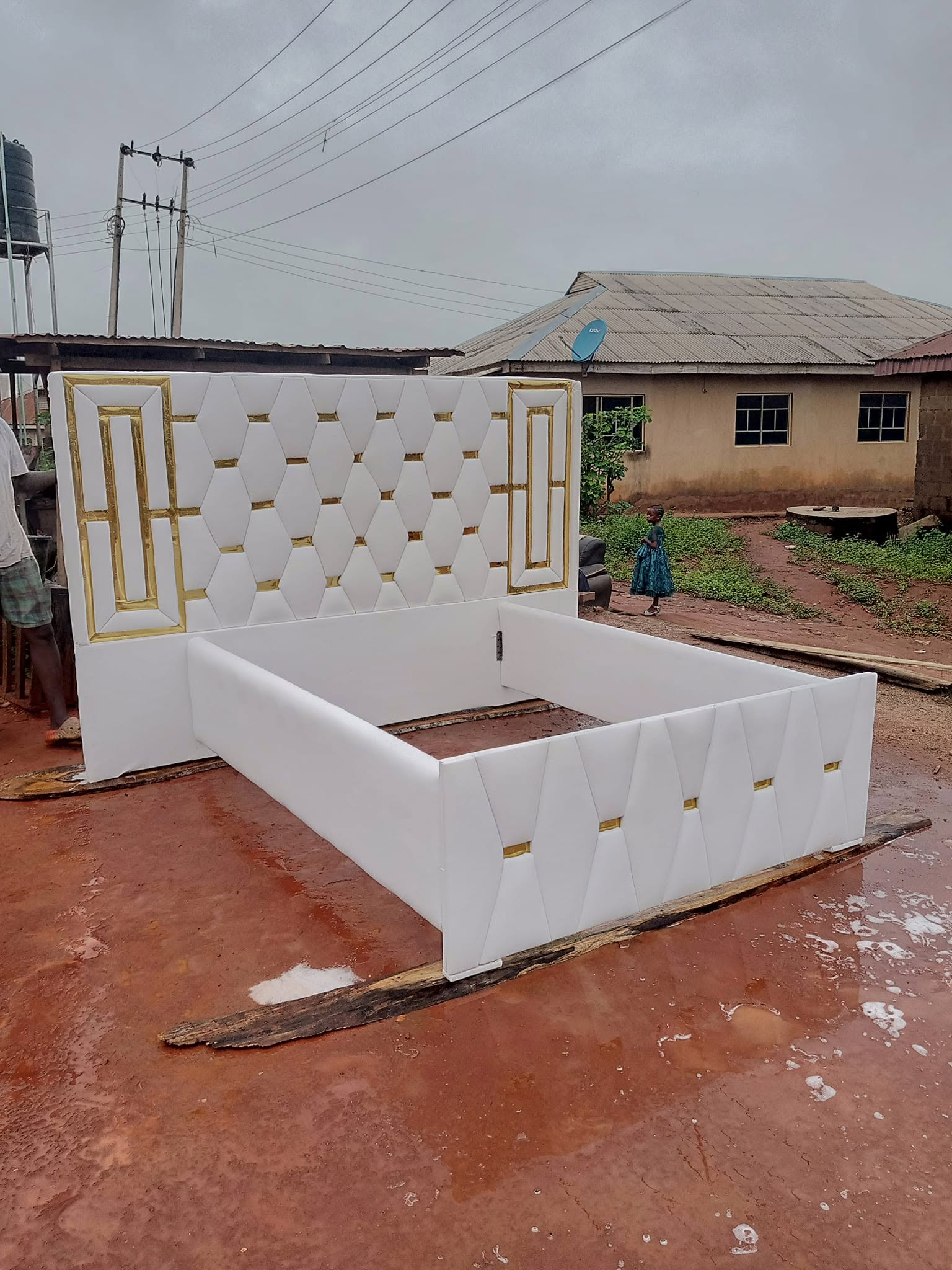 Wide workshop view of a white and gold upholstered bedframe
