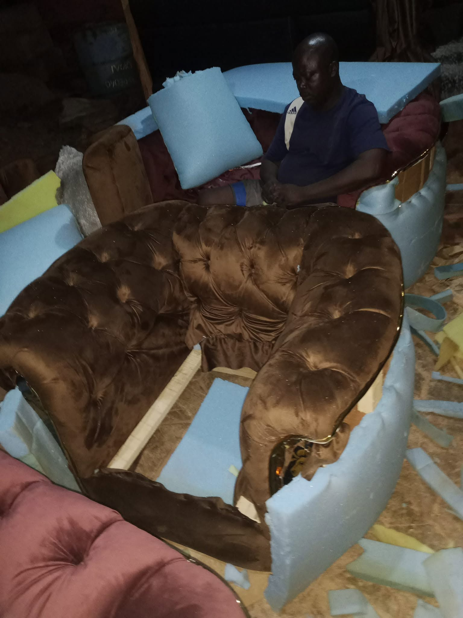 Brown tufted upholstered seating piece photographed among foam and workshop materials