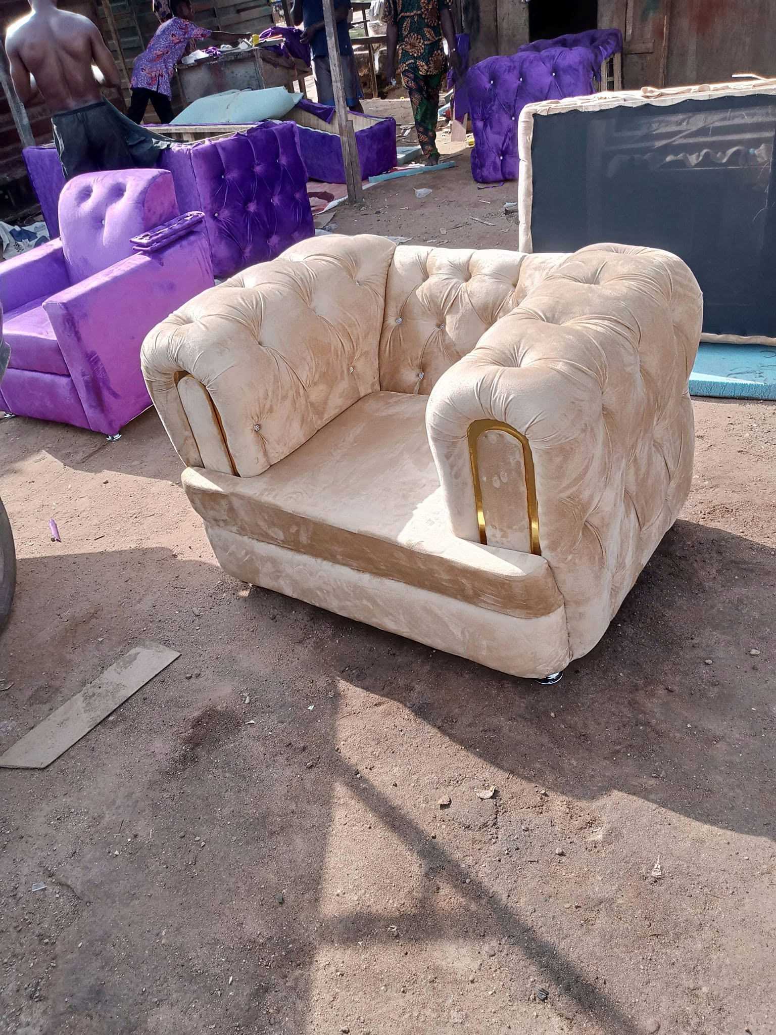 Cream tufted armchair with gold arm detail photographed in the workshop area
